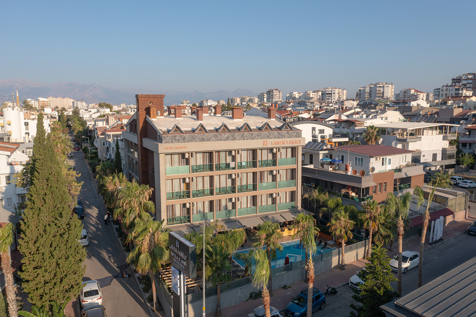 The hotel and courtyard among Lara streets, neighboring buildings and distant mountains