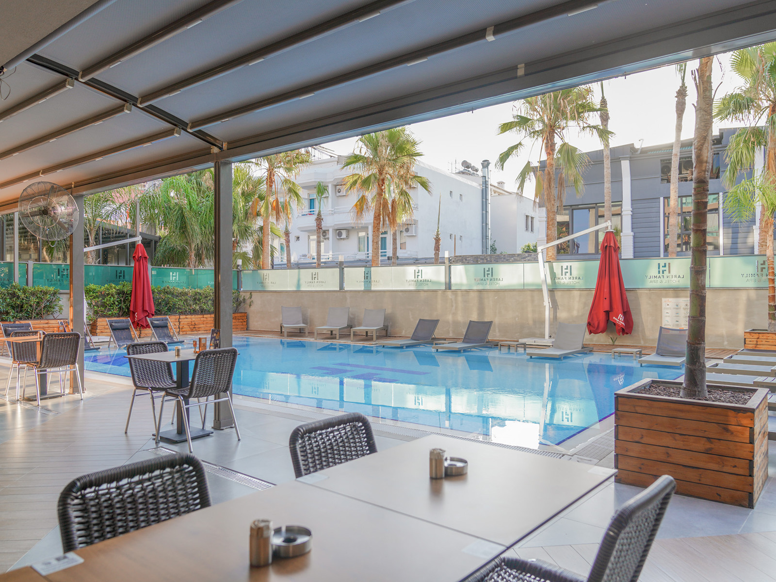 Courtyard pool with covered seating, loungers, palms and nearby buildings