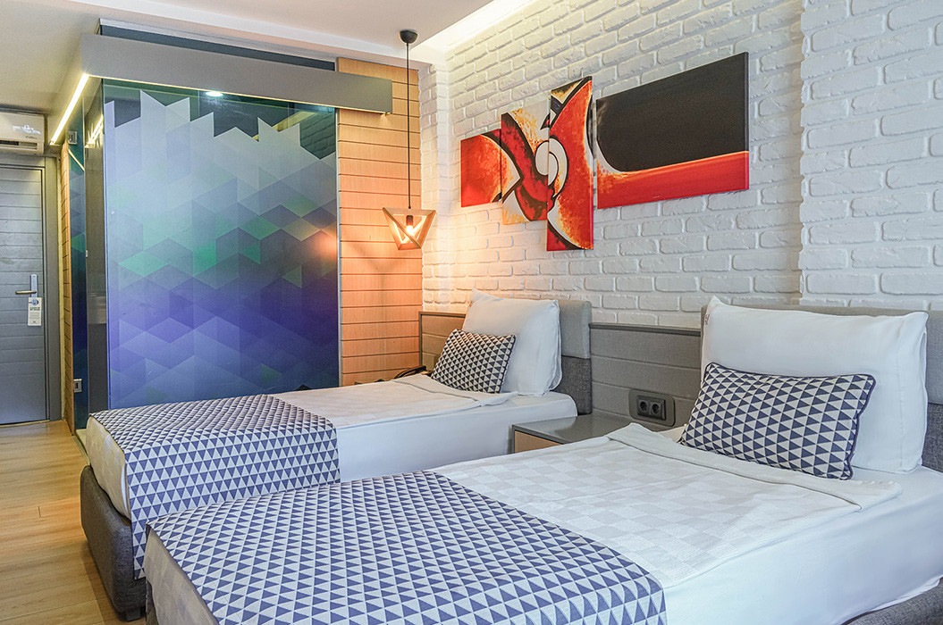 Hotel room with twin beds, patterned glass, white brick and colorful artwork